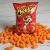 Flamin Hot Cheetos bag on white marble with scattered crunchy cheese puffs
