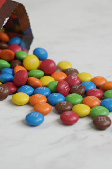 Colorful M&M candies spilling from a bag on white marble surface