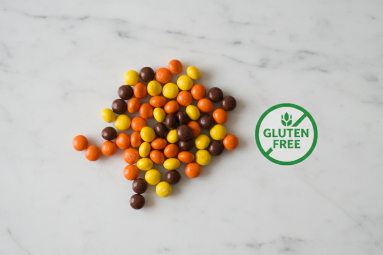 Reese's Pieces candy scattered on white marble with gluten-free badge