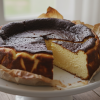 Basque burnt cheesecake on a white cake stand with dark caramelized top and creamy interior
