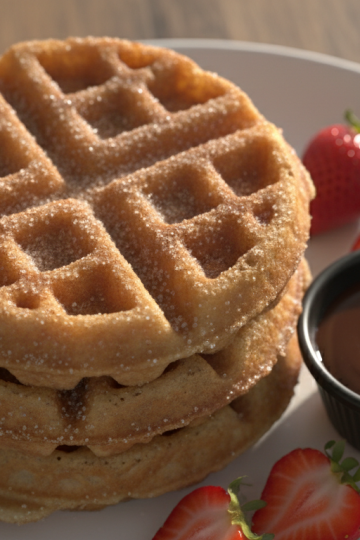 Golden churro waffles stacked with cinnamon sugar and chocolate dipping sauce