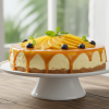 No-bake mango cheesecake on a white cake stand with vibrant golden mango glaze and fresh mango slices