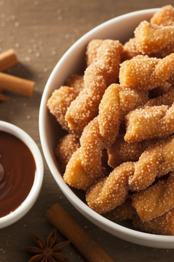 Mini churro bites in white bowl with chocolate dipping sauce
