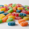 Colorful Sour Patch Kids candy scattered on white surface